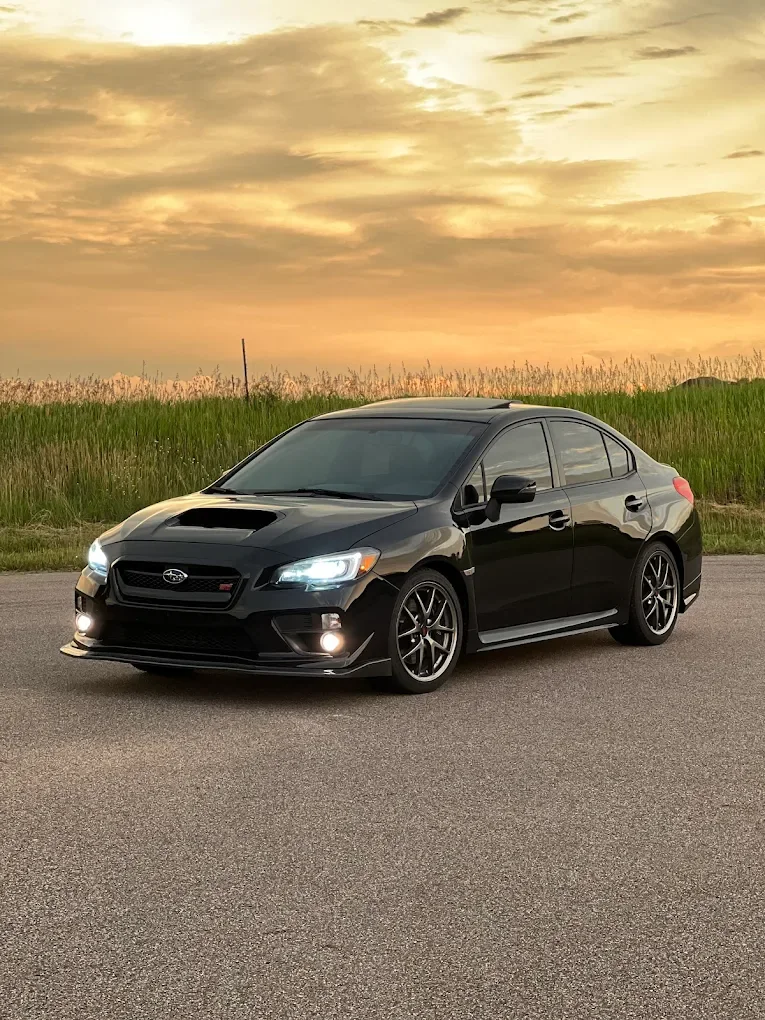 Black Subaru WRX with tinted windows at sunset